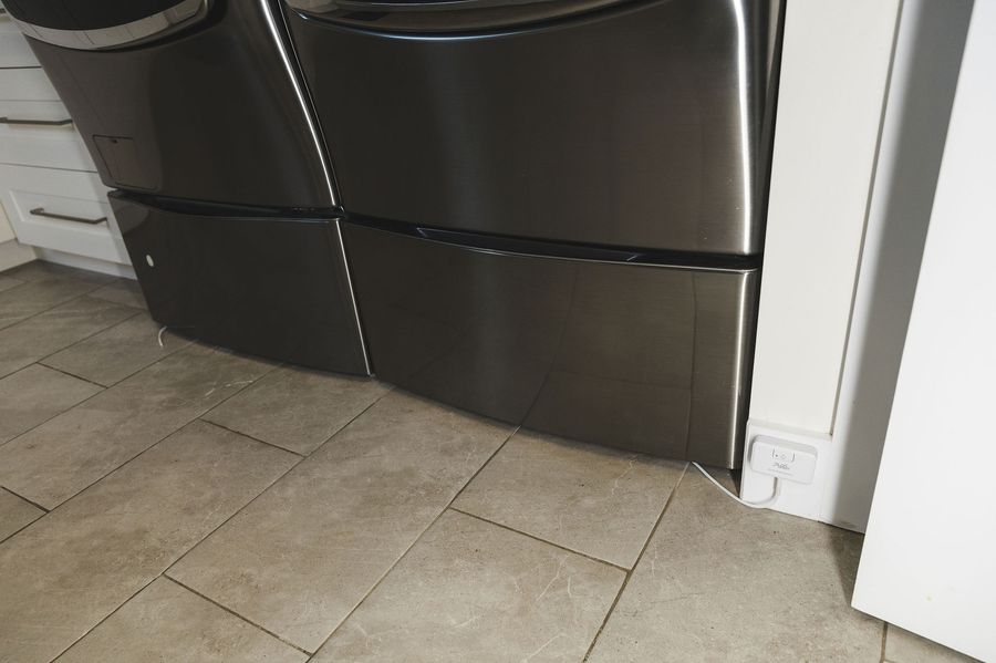 PuzL Detect mounted low beside a washer and dryer with the cable along the pedestal